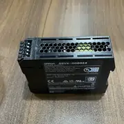 Omron S8VK-G06024 60 W 24 VDC 2.5 A PSU - front view showing the slim 32 mm wide form factor, the input/output terminal blocks with finger-safe covers, the V.ADJ output voltage adjustment trimmer, and the green DC ON LED