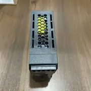Omron S8VK-S06024 mounted on a DIN rail in an outdoor control panel - the green DC ON LED visible and the slim 32 mm body fitting beside other PSUs