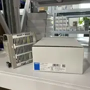 Omron S8VS-12024 switching power supply — installed on a 35 mm DIN rail in a control cabinet next to a CP1L PLC and a row of NX-IO Units, with the 24 VDC output wired to the PLC and the field devices