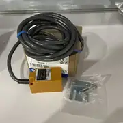 Omron TL-N10ME1 30 mm rectangular inductive sensor — front view showing the ABS plastic beige rectangular housing (30 × 30.5 × 52.5 mm) with the sensing face on the front and two orange operation indicator LEDs visible on the side