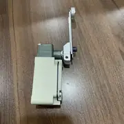 Omron WLCA12-2N-N two-circuit limit switch — installed on a conveyor transfer frame with the adjustable roller lever riding on a cam plate; the Pg13.5 conduit entry carries 6 conductors for the DPDT contact output, returning to a CJ1W-ID211 input module