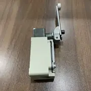 Omron WLCA12-LD-N installed on a conveyor guard with the roller lever actuated by a cam on the moving part and the LED lit