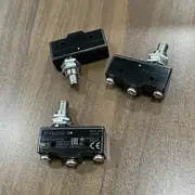 Omron Z-15GQ55-B basic switch — mounted on a cam-actuated bracket with a rotating cam wheel pressing the plunger past the 5.5 mm overtravel point on each pass