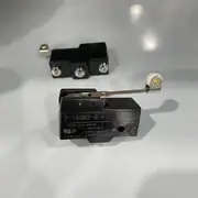 Omron Z-15GW2-B — two black Z-15 basic switches on a white surface, the front one showing the Z-15GW2-B type label, the rating 15A 125, 250 or 480VAC, the UL / CSA / CE / CCC certification marks, and the long steel hinge lever with the white nylon roller